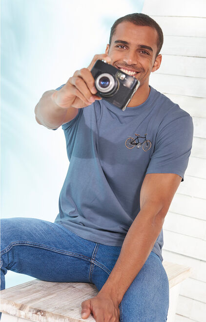 Man holding camera wearing a blue t shirt and blue jeans