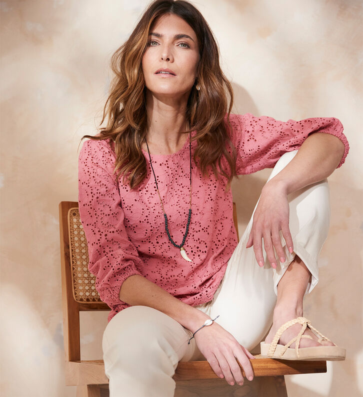 Woman wearing pink broderie anglaise top, white trousers and sandals
