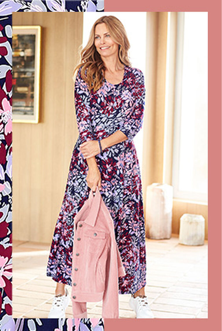 Woman standing holding a cord jacket wearing a Cotton Traders Floral Maxi Dress