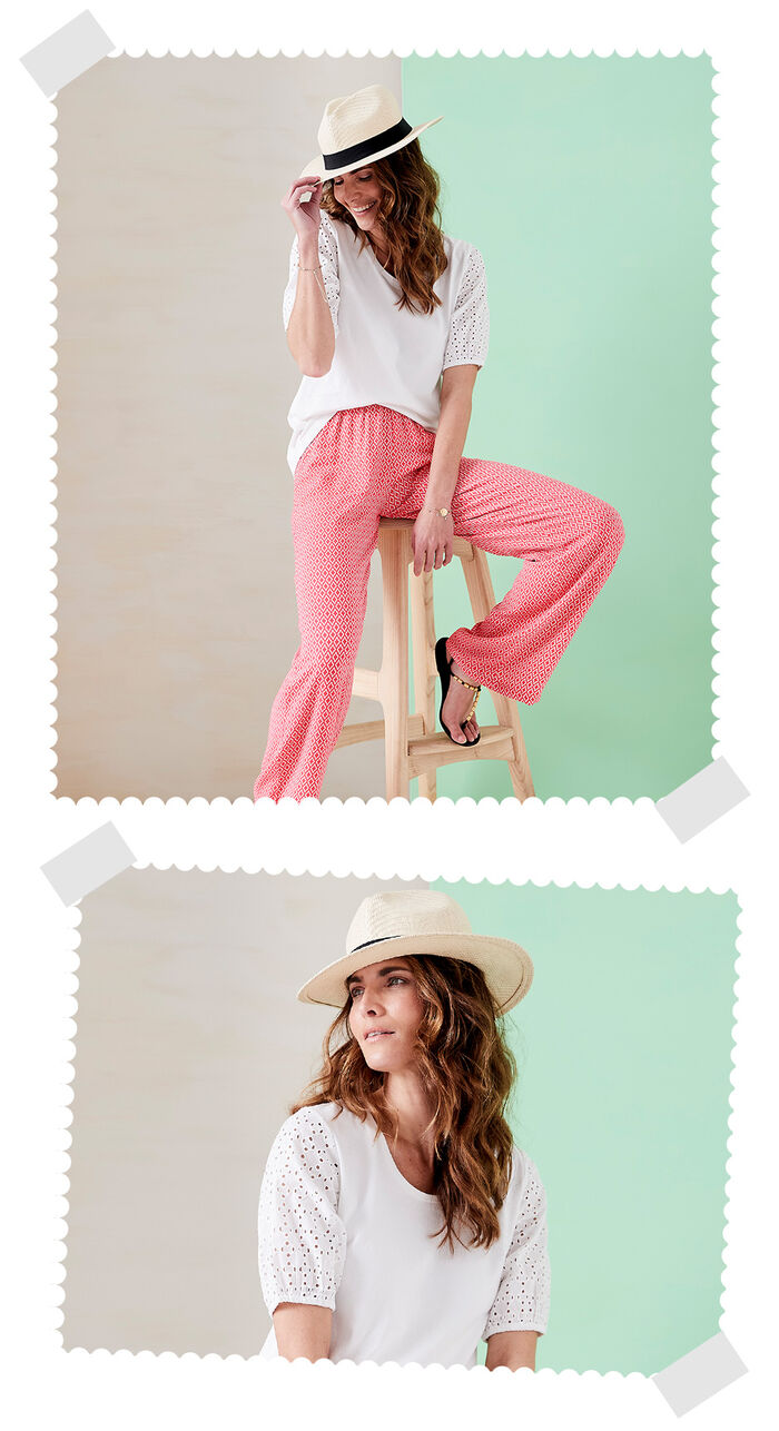 Two images of a woman sat on a wooden chair. In the first image she's wearing Cotton Traders patterned red trousers, a white t-shirt and a white hat with a black trim. On the second image she's looking off the side and is wearing a white crew neck t-shirt and hat.