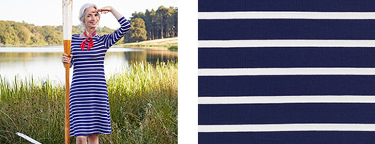Two images. A woman wears a blue and white boat shirt dress with stripes across it. She also wears a red neckerchief and holds a boat ore in her hand. The second image is a close-up shot of the blue and white striped pattern