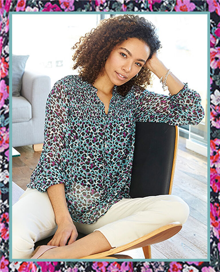 Woman sitting in chair wearing a Cotton Traders Floral Long Sleeve Blouse