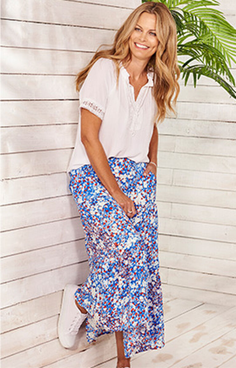 Woman wearing white top and blue floral skirt
